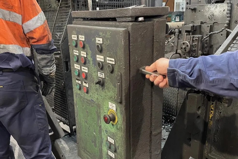 Two men using dry ice cleaning on a machine in a factory.