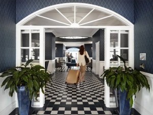 A woman is walking down a hallway with a suitcase.