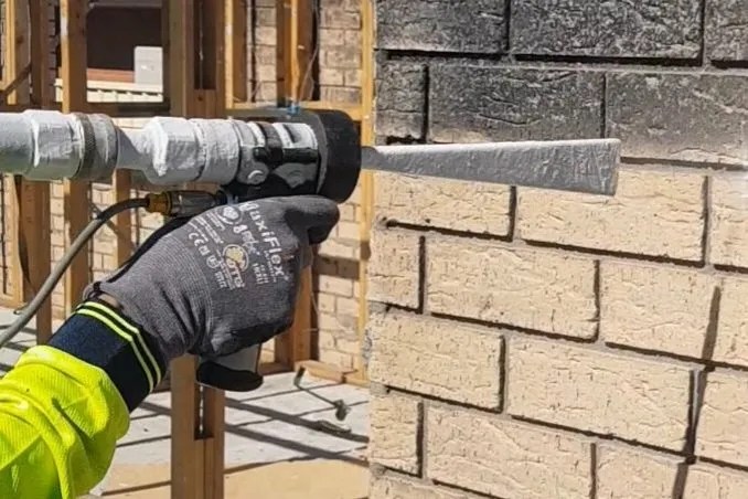 A man is using dry ice to clean a brick wall.