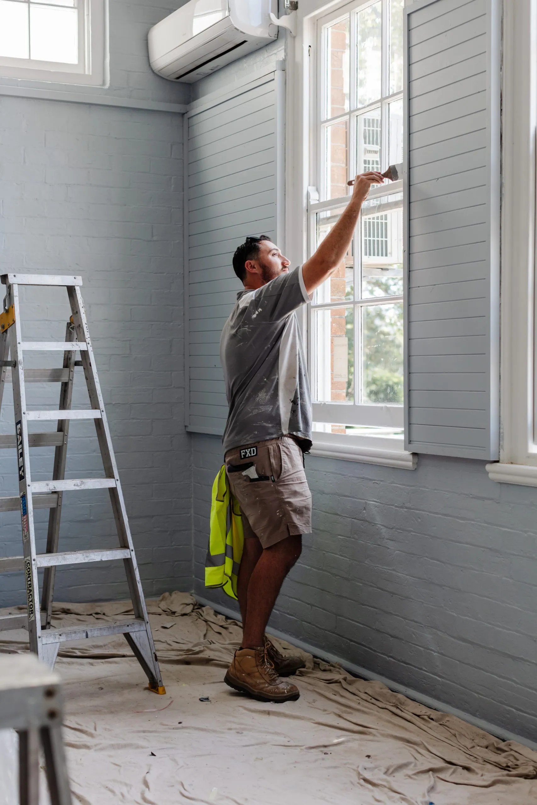 A man is painting a room with a ladder.