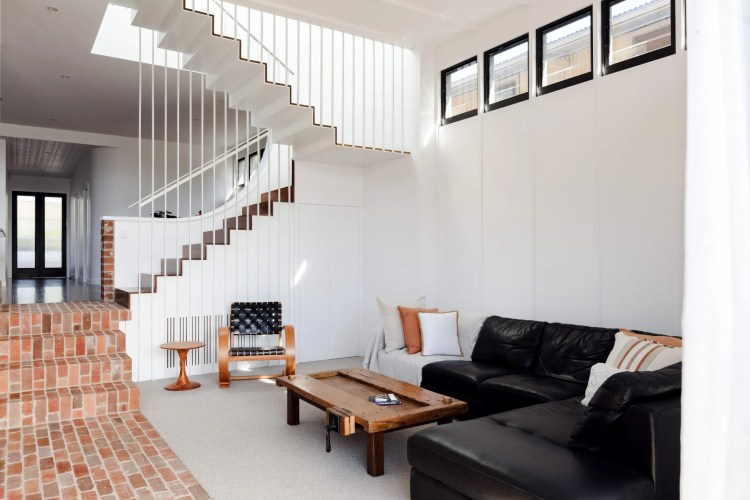 A Denison Street living room adorned with black furniture and a staircase. A Denison Street living room adorned with black furniture and a staircase.