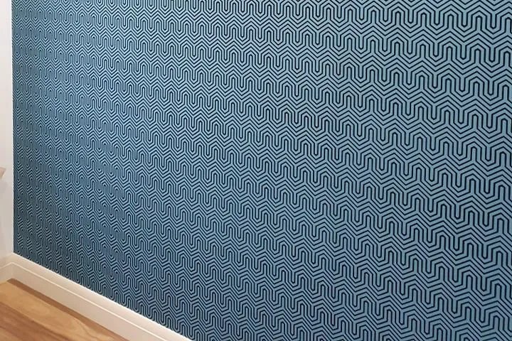 A room with a blue residential wallpaper and a wooden floor.